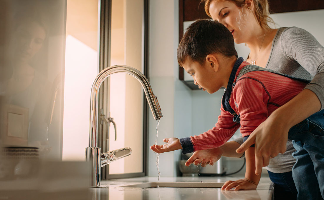 Child holds hand under sink tap Child holds hand under sink tap
